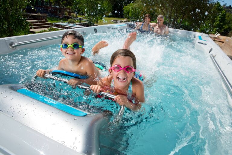 A family with kids play in an Endless Pools swim spa in summer